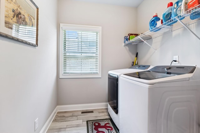 clothes washing area with light hardwood / wood-style floors and washing machine and clothes dryer