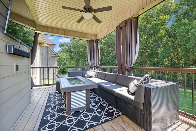 wooden terrace with ceiling fan and an outdoor living space with a fire pit