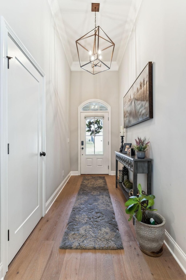 entryway featuring hardwood / wood-style floors, crown molding, and an inviting chandelier