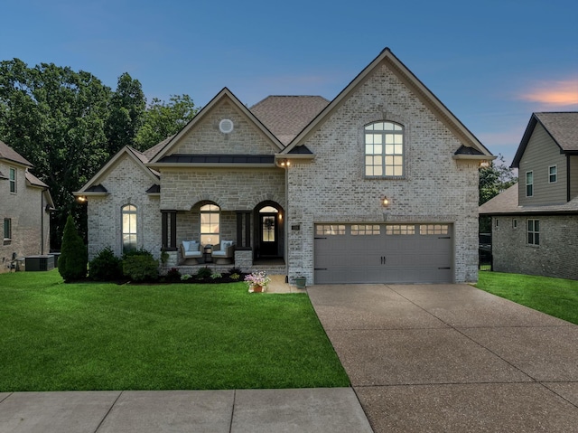 french provincial home featuring a yard, a garage, and central AC unit