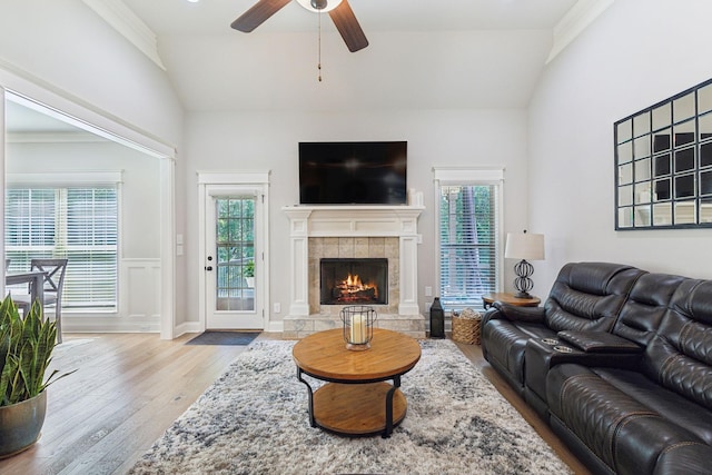 living room featuring ornamental molding, vaulted ceiling, ceiling fan, light hardwood / wood-style flooring, and a fireplace