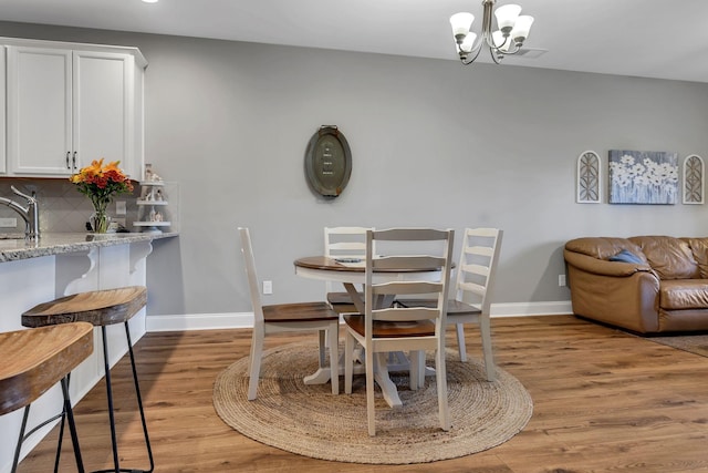 dining room with sink, light hardwood / wood-style flooring, and a chandelier