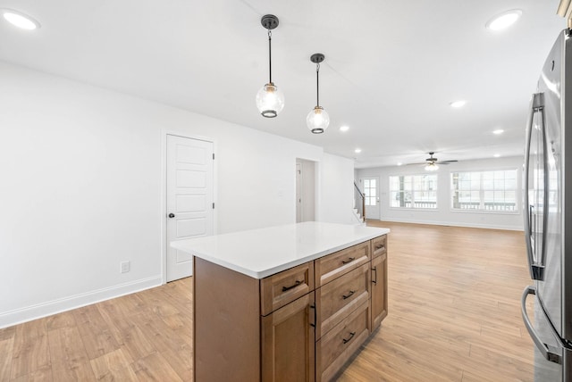 kitchen with pendant lighting, a center island, ceiling fan, light hardwood / wood-style floors, and stainless steel refrigerator