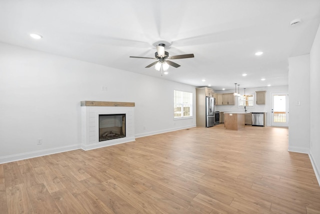 unfurnished living room with a fireplace, light wood-type flooring, and ceiling fan