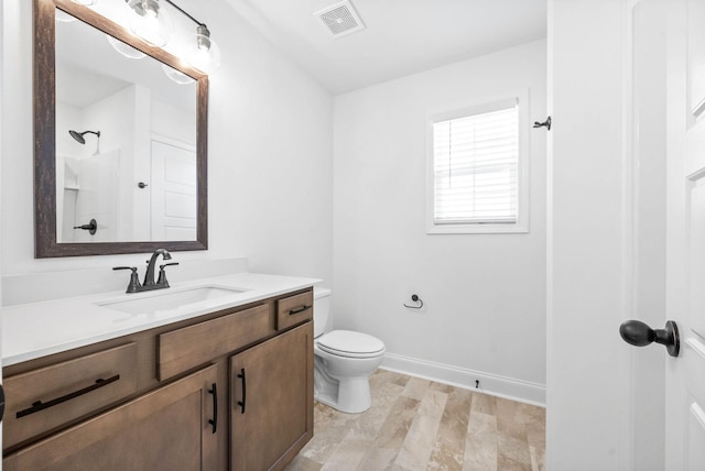 full bath featuring visible vents, toilet, vanity, baseboards, and walk in shower