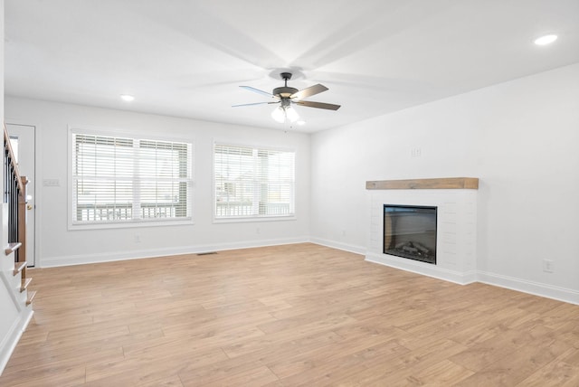 unfurnished living room with ceiling fan, light hardwood / wood-style floors, and a fireplace