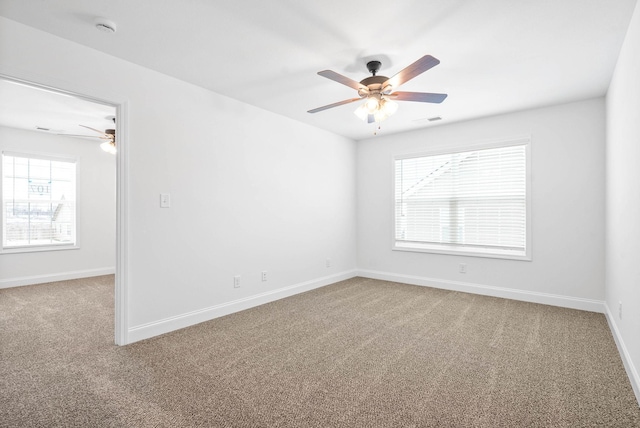 unfurnished room featuring carpet floors, a ceiling fan, visible vents, and baseboards