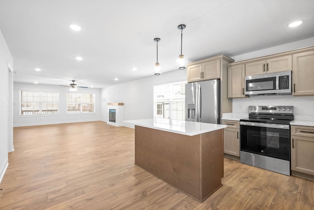 kitchen featuring a center island, hanging light fixtures, light hardwood / wood-style flooring, ceiling fan, and appliances with stainless steel finishes