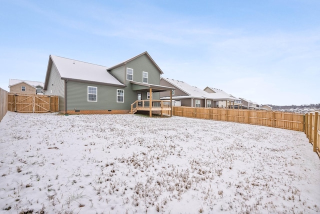 snow covered rear of property with a deck