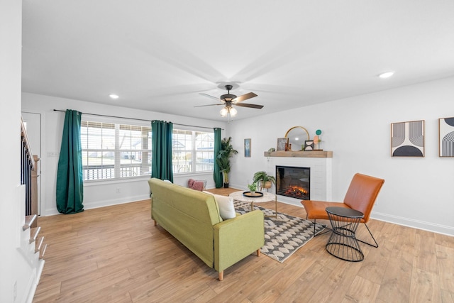 living room featuring light wood-type flooring, a brick fireplace, baseboards, and recessed lighting