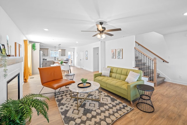 living area with baseboards, stairway, light wood-style floors, a fireplace, and recessed lighting