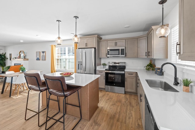 kitchen featuring a breakfast bar area, light countertops, light wood-style flooring, appliances with stainless steel finishes, and a sink