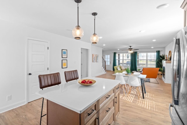 kitchen with light wood-style floors, a center island, a breakfast bar, and freestanding refrigerator