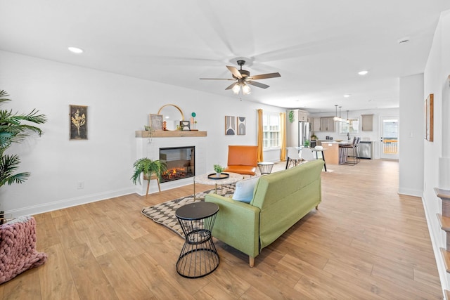 living room featuring light wood-style floors, a glass covered fireplace, a wealth of natural light, and recessed lighting