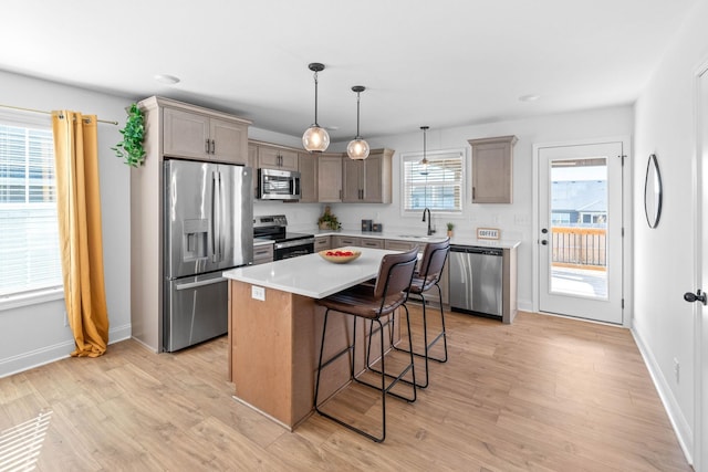 kitchen featuring a center island, stainless steel appliances, light countertops, light wood-style floors, and a kitchen breakfast bar