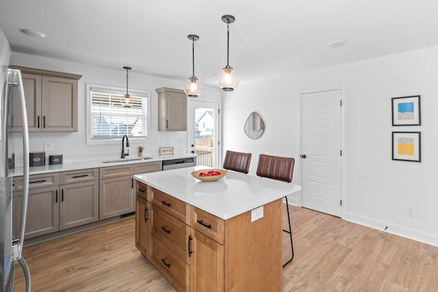 kitchen with stainless steel appliances, a breakfast bar, a sink, and light wood-style flooring