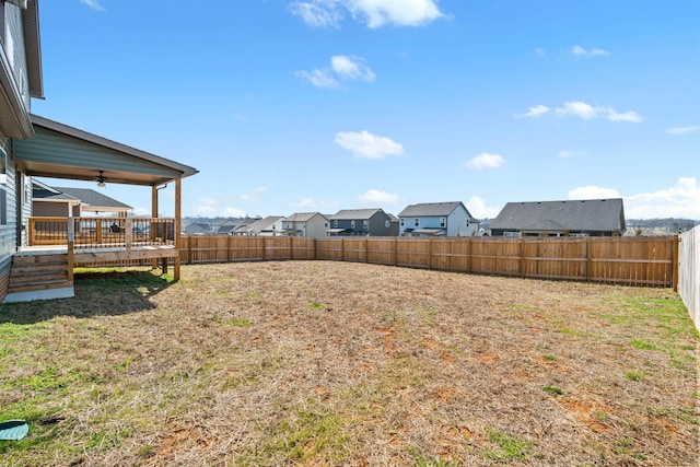 view of yard with ceiling fan, a fenced backyard, a residential view, and a deck