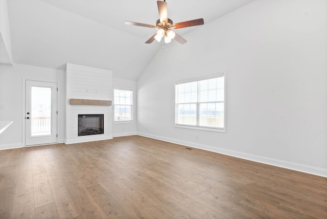 unfurnished living room with hardwood / wood-style floors, a large fireplace, high vaulted ceiling, and ceiling fan