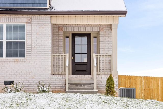 snow covered property entrance featuring central AC unit