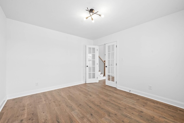 unfurnished room featuring french doors, hardwood / wood-style flooring, and an inviting chandelier