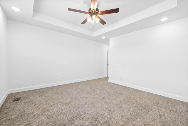 unfurnished room with carpet flooring, a raised ceiling, and ceiling fan