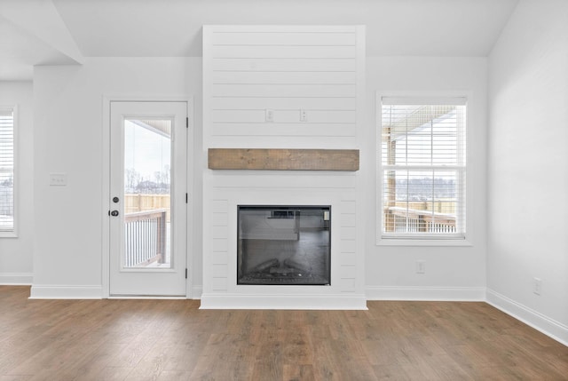 unfurnished living room featuring hardwood / wood-style floors, lofted ceiling, and a fireplace