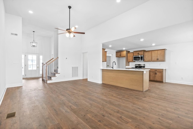 kitchen with decorative light fixtures, dark hardwood / wood-style flooring, stainless steel appliances, and a high ceiling