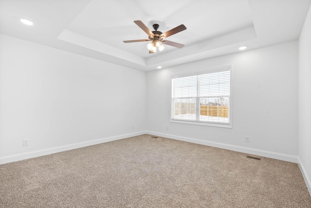 carpeted empty room featuring a tray ceiling and ceiling fan