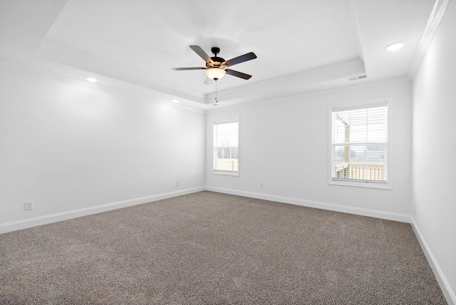 empty room featuring carpet floors, visible vents, baseboards, ornamental molding, and a raised ceiling