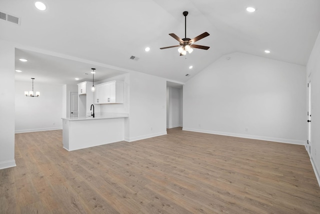 unfurnished living room with visible vents, lofted ceiling, ceiling fan with notable chandelier, light wood-type flooring, and recessed lighting