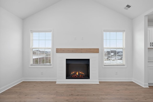 unfurnished living room with lofted ceiling, light wood-type flooring, plenty of natural light, and visible vents