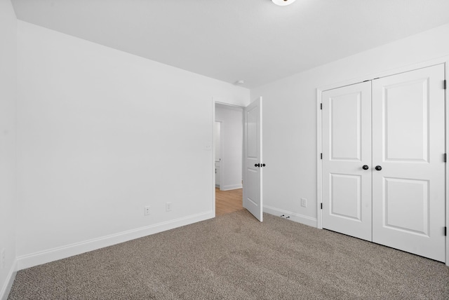 unfurnished bedroom featuring carpet floors, a closet, and baseboards