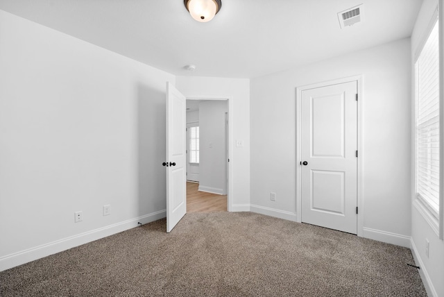 unfurnished bedroom with carpet, visible vents, and baseboards