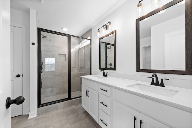 bathroom with a stall shower, a sink, and double vanity