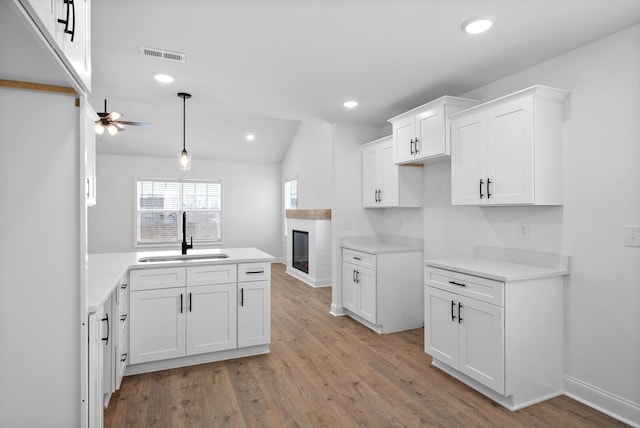 kitchen with visible vents, light wood-type flooring, white cabinetry, a sink, and recessed lighting