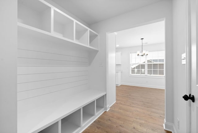 mudroom with a chandelier, baseboards, and wood finished floors