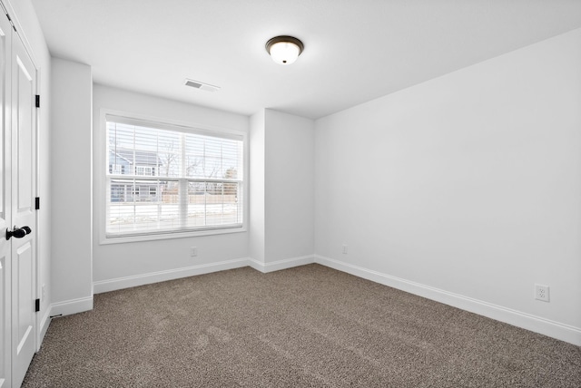 carpeted spare room with visible vents and baseboards