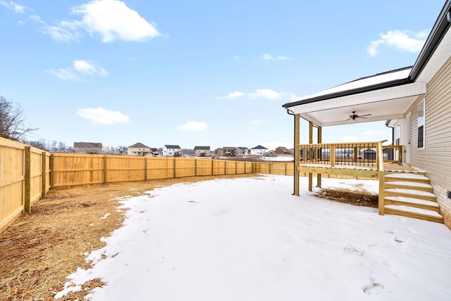 yard covered in snow featuring a ceiling fan, stairway, a fenced backyard, and a deck