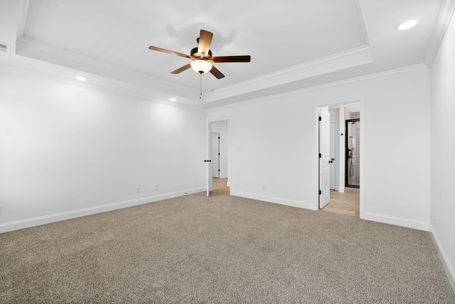 spare room with baseboards, a tray ceiling, crown molding, and light colored carpet