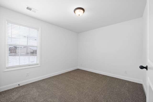 spare room featuring baseboards, visible vents, and dark carpet