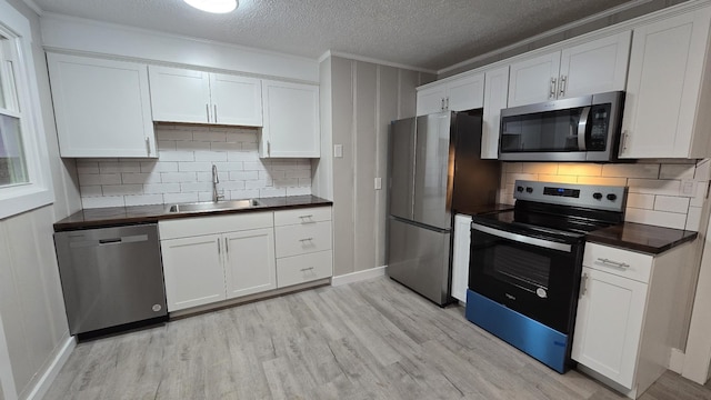 kitchen with appliances with stainless steel finishes, white cabinetry, and sink