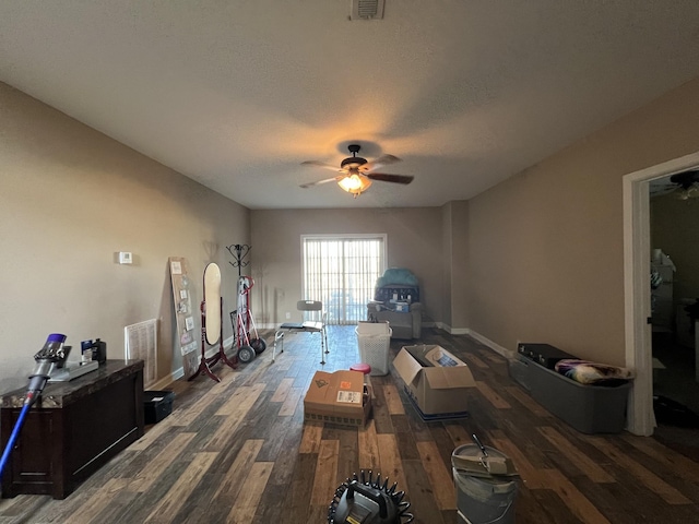 living room with a textured ceiling, ceiling fan, and dark hardwood / wood-style floors