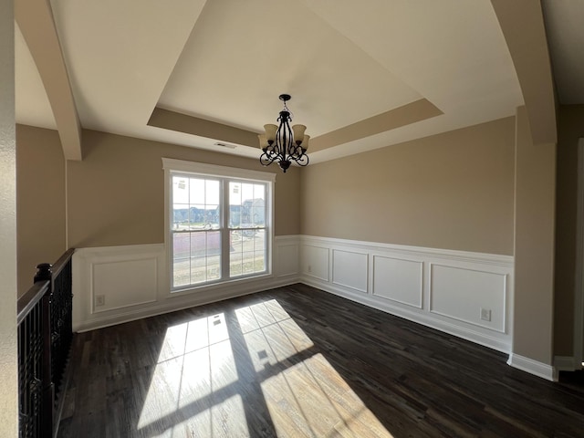 unfurnished dining area with a raised ceiling, dark hardwood / wood-style floors, and a notable chandelier