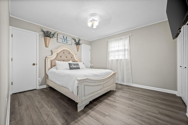 bedroom with ceiling fan, crown molding, hardwood / wood-style floors, a textured ceiling, and a closet