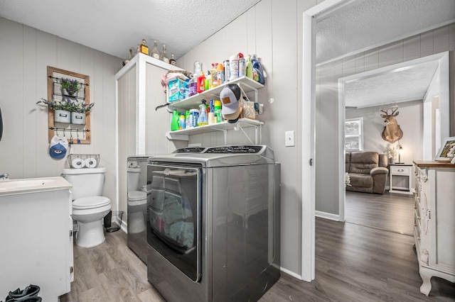 washroom featuring hardwood / wood-style flooring, washer and clothes dryer, sink, and a textured ceiling