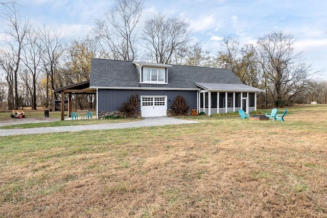 rear view of property with a sunroom, a yard, and an outdoor fire pit