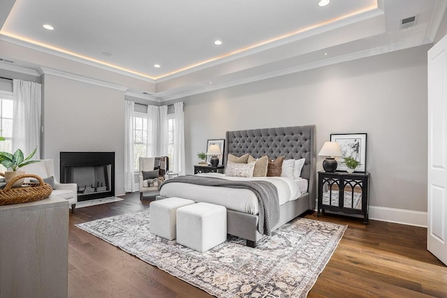 bedroom with dark hardwood / wood-style floors and a tray ceiling