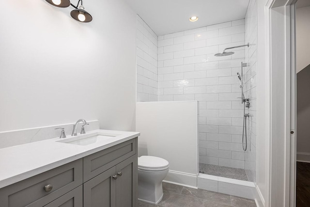 bathroom featuring tiled shower, vanity, toilet, and tile patterned flooring