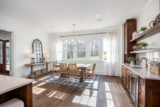 dining room with dark hardwood / wood-style flooring, sink, a notable chandelier, and ornamental molding