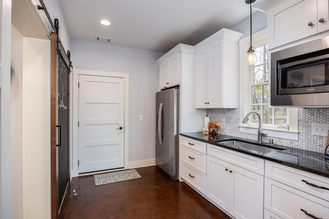 kitchen with sink, a barn door, decorative light fixtures, white cabinets, and appliances with stainless steel finishes